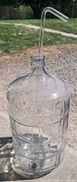 Full view of clear glass carboy with straw inserted