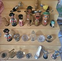 Overall view of carved, glass and metal stoppers on rack