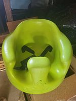 Top view of green Bumbo infant seat showing harness and contoured interior