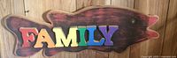 Full view of carved wooden fish plaque with multicolored FAMILY letters