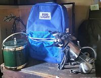 Overall view of Bud Light cooler backpack, green ice bucket, and metal dog bottle holder