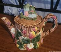 Right side of teapot showing lid with frogs, berries and flowers detail