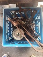 Top view of milk crate holding assorted rusty tools and hardware