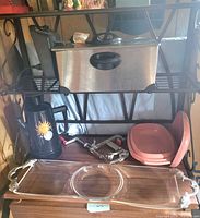 All items arranged on shelf: deep fryer, percolator, Tupperware steamer, apple peeler, clear serving tray with dip bowl