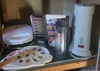 Pie maker, toaster oven pans in rack, iced tea brewer, infusion bottle visible
