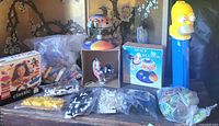 Group shot of all items on table: Lego Classic box, loose Lego bricks, Space Station toy, Homer Simpson Pez, Roxx discs