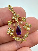 Front view of pendant showing amethyst drop, seed pearls and gold floral design