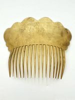 Front view of brass hair pick showing engraved floral pattern and tines