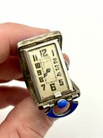 Front view of folded clock displaying dial and blue enamel handle