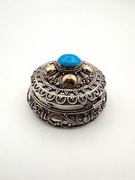 Top and side view of ornate sterling silver trinket box showing turquoise cabochon and gold accents