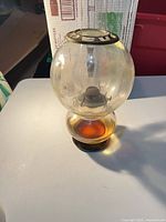 Full view of glass oil lamp with globe