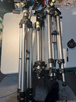 Three folded aluminum tripods side by side on table