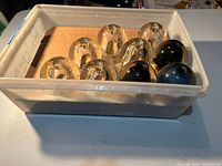 Plastic tote holding clear and dark glass globes