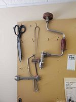 Scissors, coping saw frame, hand brace drill, open-end wrench on pegboard