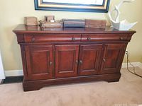 Front view of cherry-stained wood sideboard showing two drawers and four cabinet doors