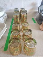 Front view showing alternating highball and lowball tumblers with gold lattice and olive panels