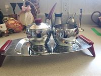 Sugar bowl with lid, creamer, spoon, and handled tray on countertop