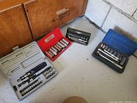 Four plastic tool cases opened showing socket and bit sets