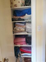 Closet shelves filled with folded linens assorted colors and sizes