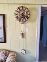 Full view of wall-mounted skeleton gear clock with pendulum and weight