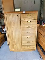 Front view showing cabinet door and six drawers with brass-tone pulls