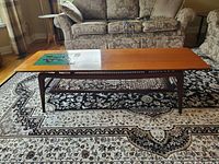 Full view of rectangular coffee table showing wood top, cane shelf, tapered legs