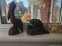 Overview showing tan elephant at right and dark grey beaver center on windowsill