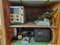 Oscilloscope, soldering station, shellac bottle, flashlight, case, accessories on shelves