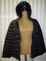 Front view of black quilted hooded jacket on mannequin, zipper open