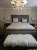 Full view of assembled king bed showing headboard, footboard, side rails, box springs under linens