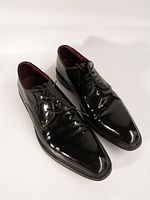 Full view of both shoes showing patent leather finish and laces