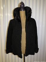 Front view of black shearling coat on dress form