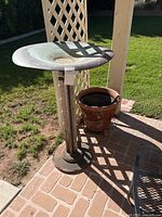 Birdbath on pedestal next to planter