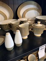Cabinet top shelf with serving pieces, cups, shakers shows pattern and gold trim