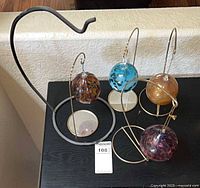 Group of four glass ornaments on four metal stands