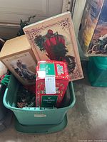 Overview of green plastic bin and boxed items including fiber optic tree, porcelain angel box and wall décor