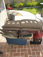Stack of assorted patio cushions in tote and crate