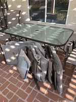 Glass-top patio table with stacked packaged chairs/loungers