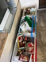 Three plastic bins on garage floor containing holiday décor