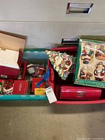 Two storage bins with assorted Christmas decor including boxed ornaments, ceramic platter and red cases
