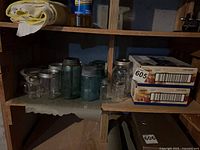 Shelf with vintage clear and aqua canning jars alongside two sealed Ball jelly-jar cases
