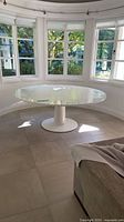 White round pedestal table in breakfast nook showing glossy lacquer surface and overall form