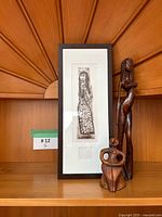 Framed print, wood standing figure, ceramic seated figure on shelf