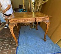 Side view of carved wood games table showing legs and apron