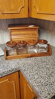 Bread box with roll-top door and set of four glass canisters in wood rack
