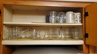 Upper and lower cupboard shelves showing all glassware and ceramic steins