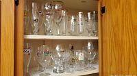 Cabinet view showing two shelves filled with assorted branded beer glasses