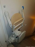 Folded Handicare stairlift at top of stairs showing seat, armrests, footrest