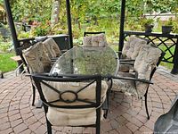 Overall view of glass table and six cushioned chairs on patio