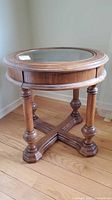 Full view of round glass-top end table showing legs and stretcher